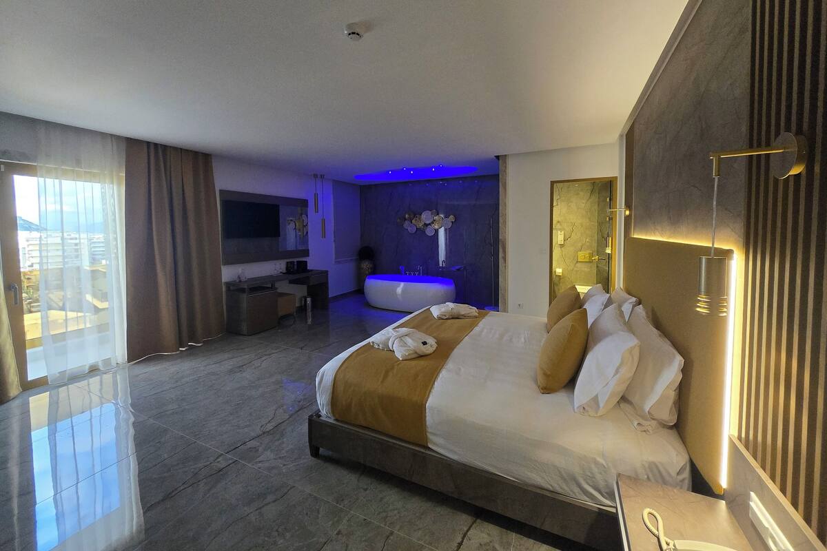Una habitación de hotel moderna con una cama grande, un baño y un balcón.
