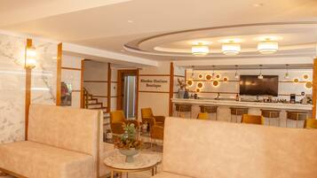 A hotel lobby with a bar area, seating, and a sign for 'Rhodos Horizon Boutique'.