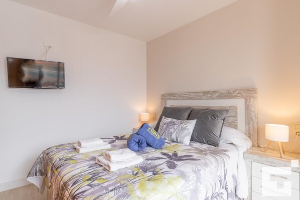 A neatly made bed with a floral bedspread, two pillows, and a folded towel. - Borumbot 38 - Grupo Turis - Calpe, Costa Blanca (Calpe)