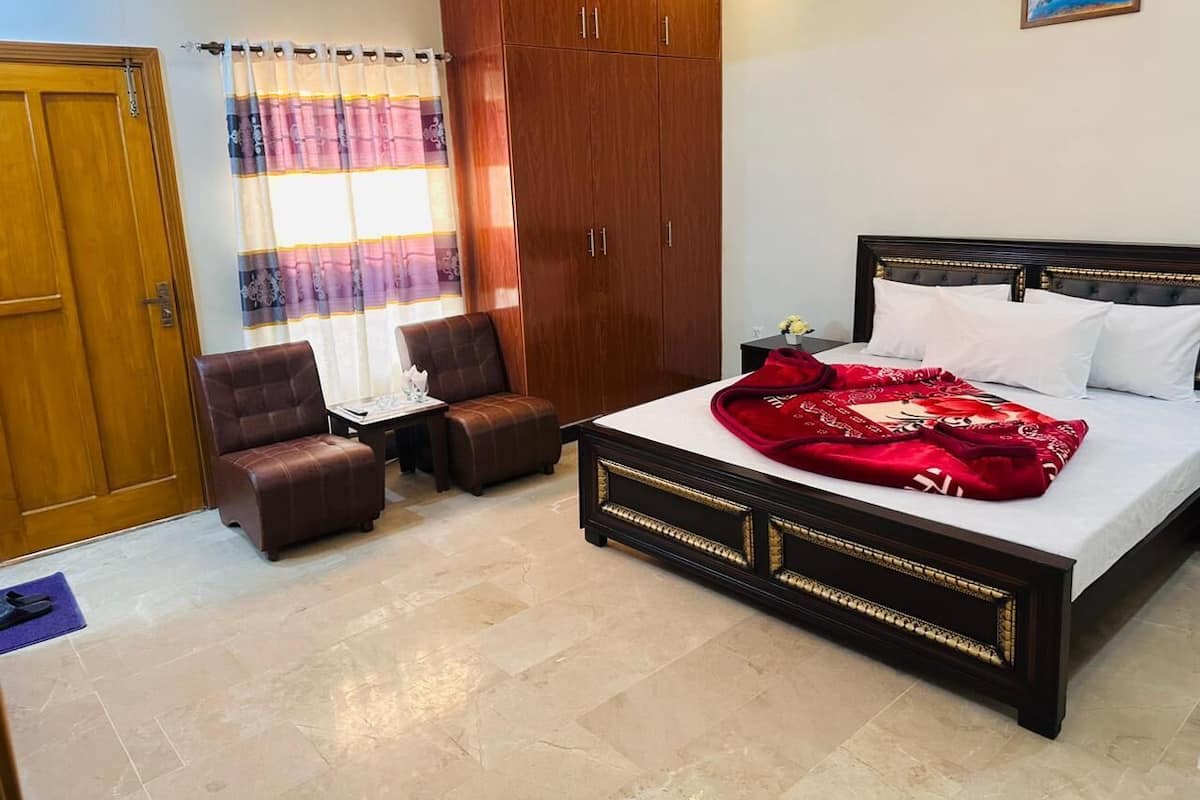 Une chambre à coucher avec un lit, une armoire, une chaise et une petite table.