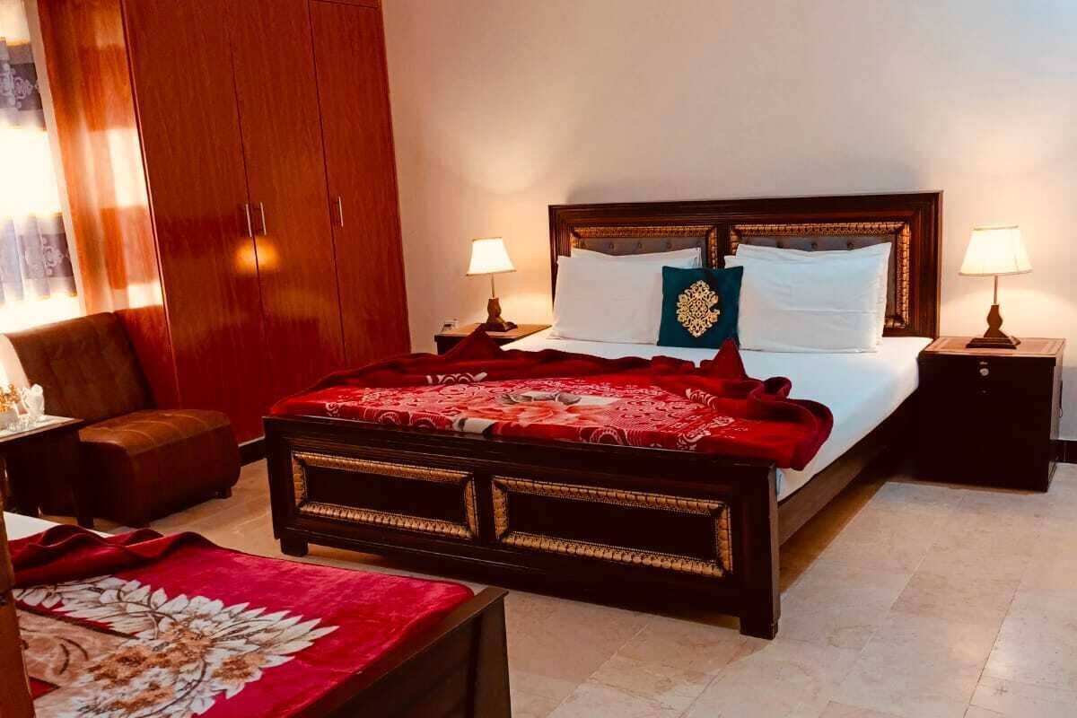 Une chambre avec un grand lit, deux tables de chevet, une armoire et un ventilateur de plafond.
