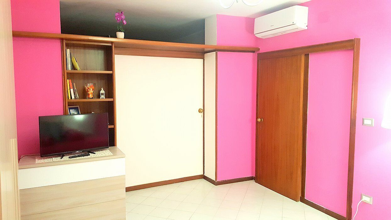 A room with a television on a stand, a wardrobe, and a door.