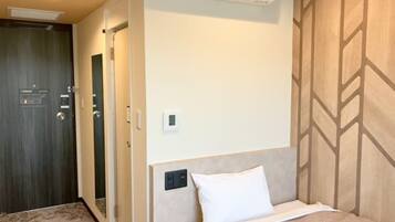 Een hotelkamer met een bed, een wandairconditioner, een deur en een behang met patroon.