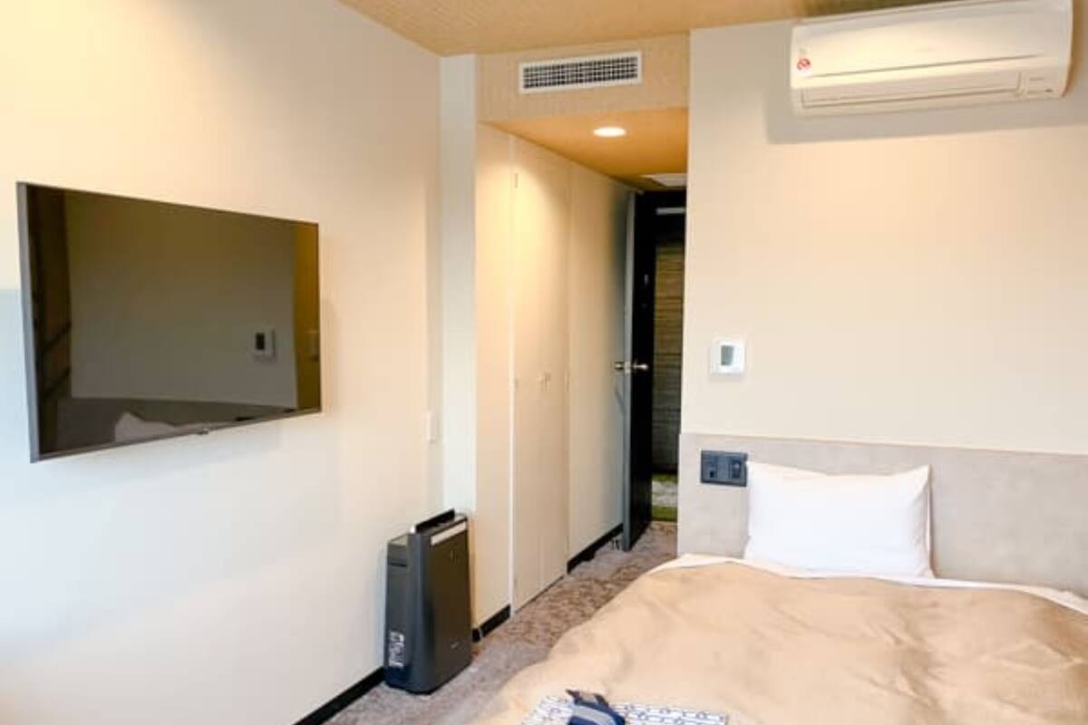 Ein Hotelzimmer mit Bett, Wandfernseher und Klimaanlage.