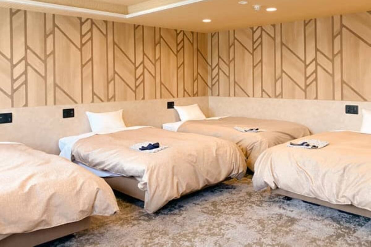 Ein Hotelzimmer mit drei Betten, einer Wand mit Muster und einem strukturierten Teppich.