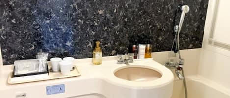 A bathroom with a marble backsplash, a sink, a mirror, and a shower.