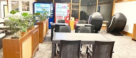 Un salón de conferencias con una larga mesa, sillas, un mostrador de recepción y una máquina expendedora.