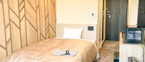A hotel room with a bed, a desk with a computer, and a door leading to another room.