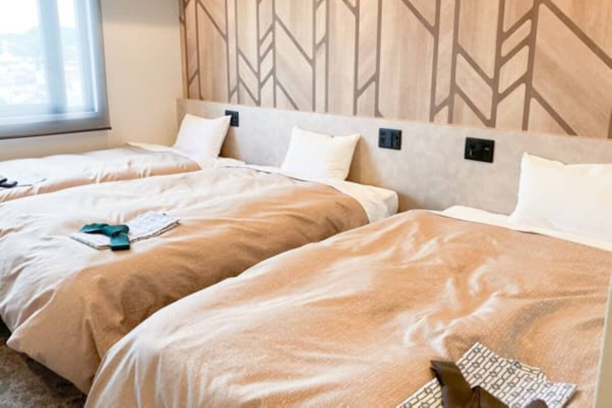 Ein Hotelzimmer mit zwei Betten, einer Wandverkleidung aus Holz und einem Fenster mit Jalousien.