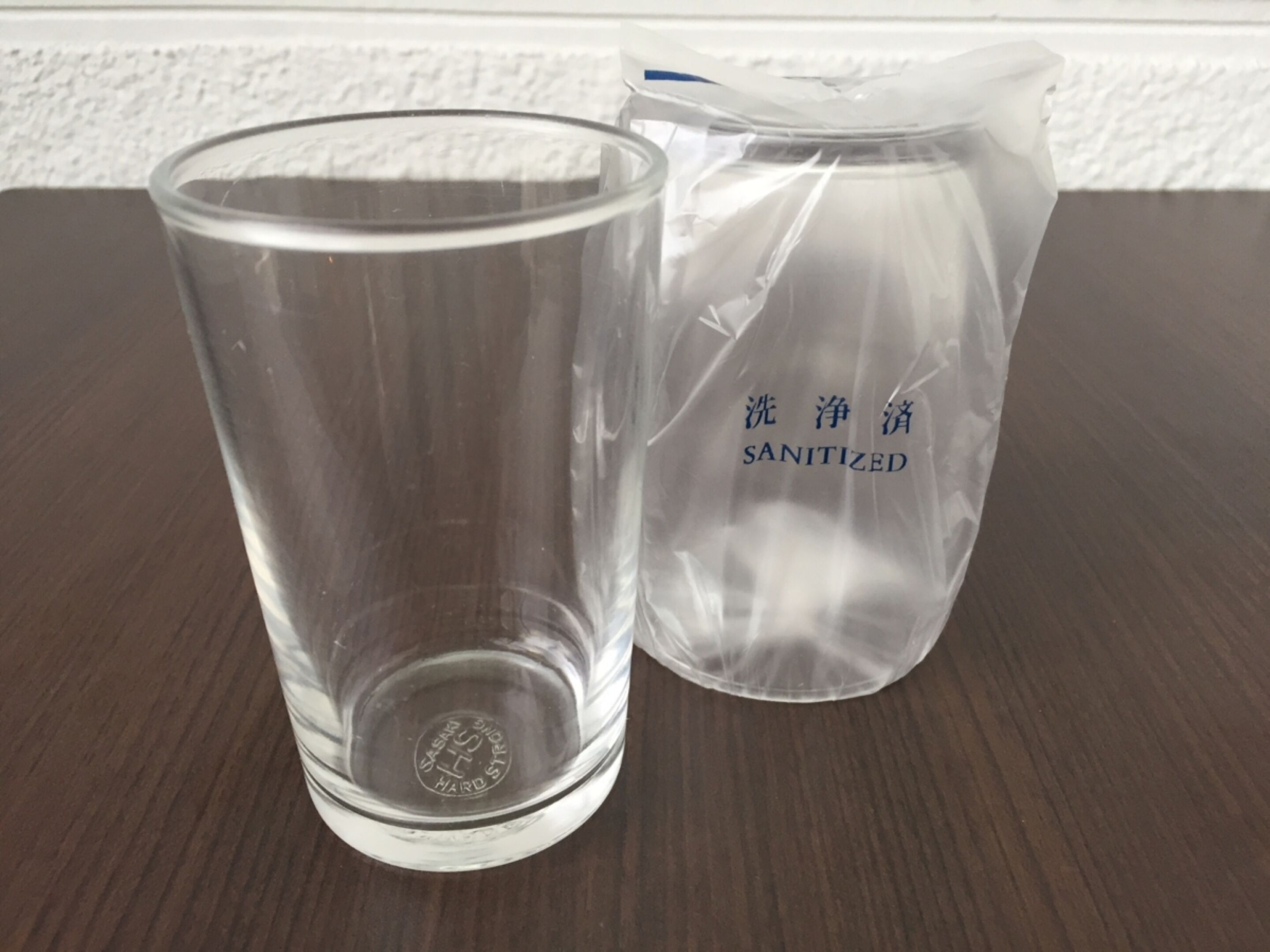 A clear glass and a plastic container with "SANITIZED" written on it.