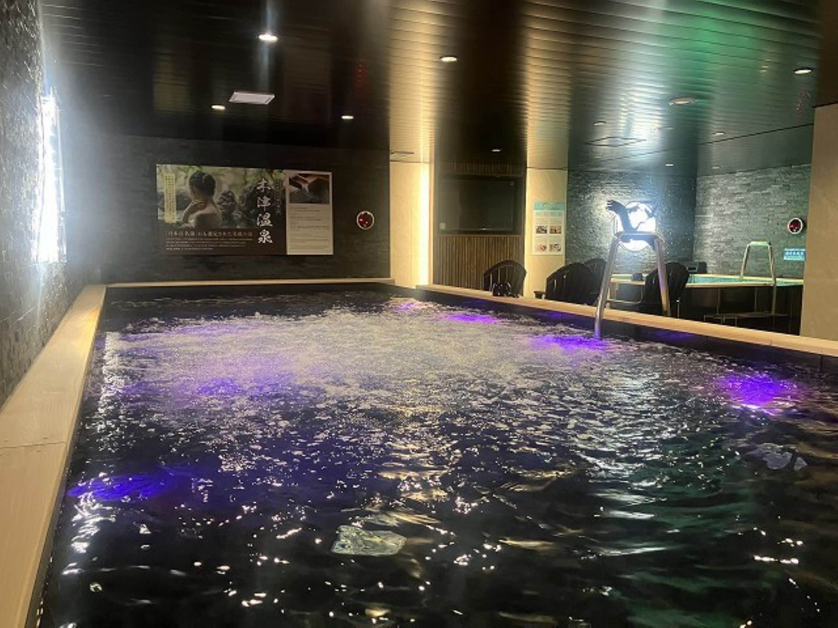 Un jacuzzi con chorros de agua, un cartel en la pared y una silla cerca de la bañera.