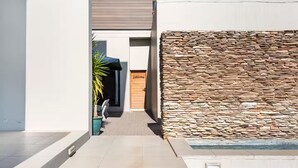 Un edificio moderno con una pared de piedra, un letrero de bienvenida y una planta en maceta.