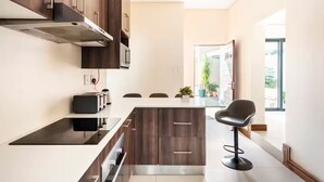 Una cocina moderna con armarios de madera oscura, horno integrado y un taburete negro.