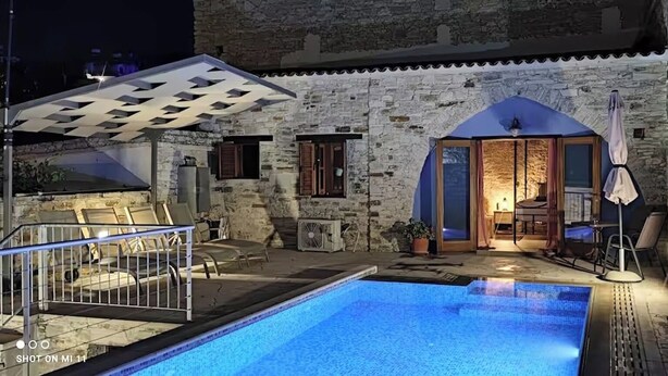 Un bâtiment en pierre doté d’une piscine, d’un espace extérieur aménagé et d’une zone couverte.