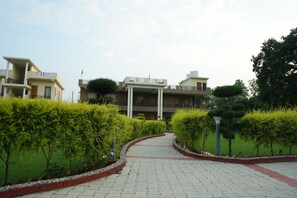 A pathway leading to a building with multiple balconies and a landscaped garden. - Vasant Corbett Resort (Ramnagar)