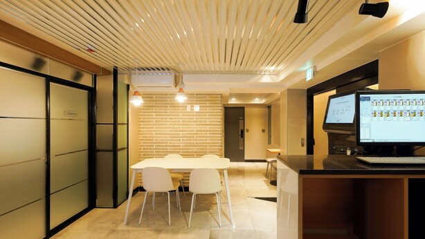 A modern kitchen with a dining area, a computer monitor, and a sign indicating a cafeteria. - Han stay (Seoul)