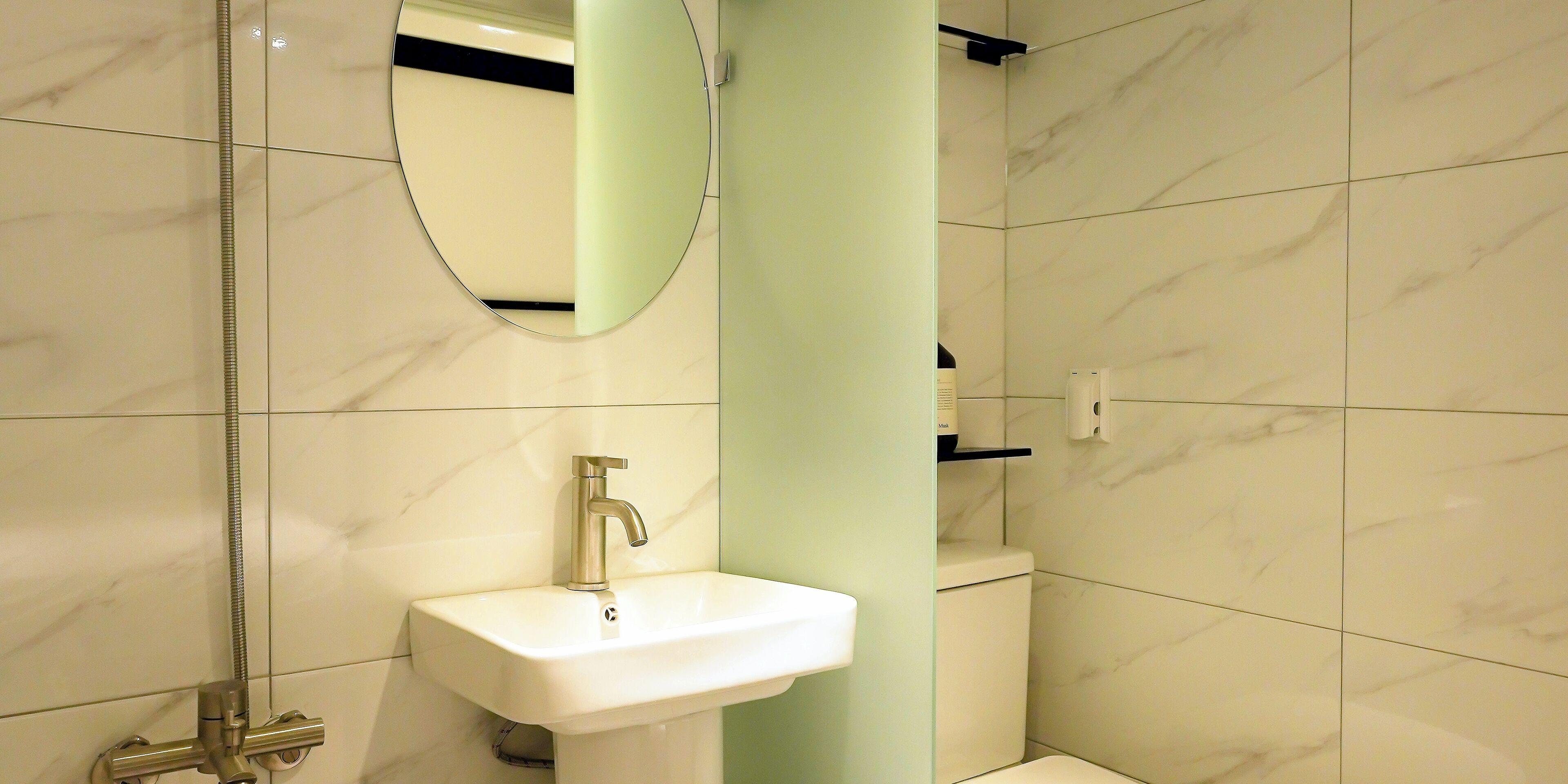 A bathroom with a white sink, a mirror, a shower, and a toilet.