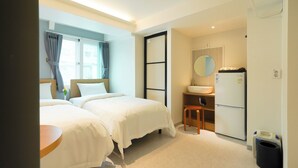 A hotel room with two beds, a small table, a sink, and a refrigerator. - Han stay (Seoul)
