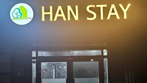 A hotel entrance with a sign reading "HAN STAY" and a logo with a green tree and a house. - Han stay (Seoul)