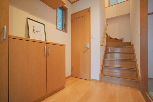 A wooden staircase leading to an upper floor, a wooden door, and a framed picture on the wall.