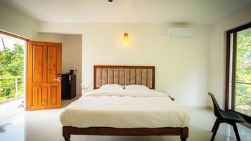 A bedroom with a wooden bed, a ceiling fan, a wall-mounted air conditioner, and a view of greenery through a large window.