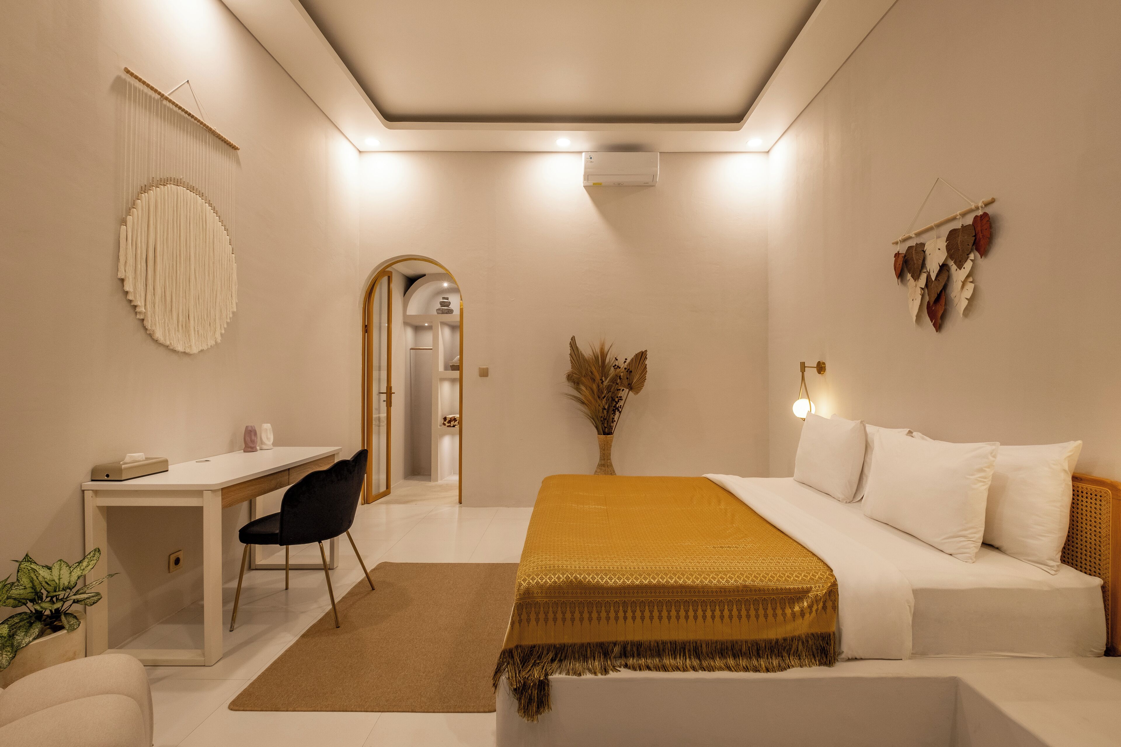 A modern bedroom with a bed, desk, chair, and a decorative wall hanging.