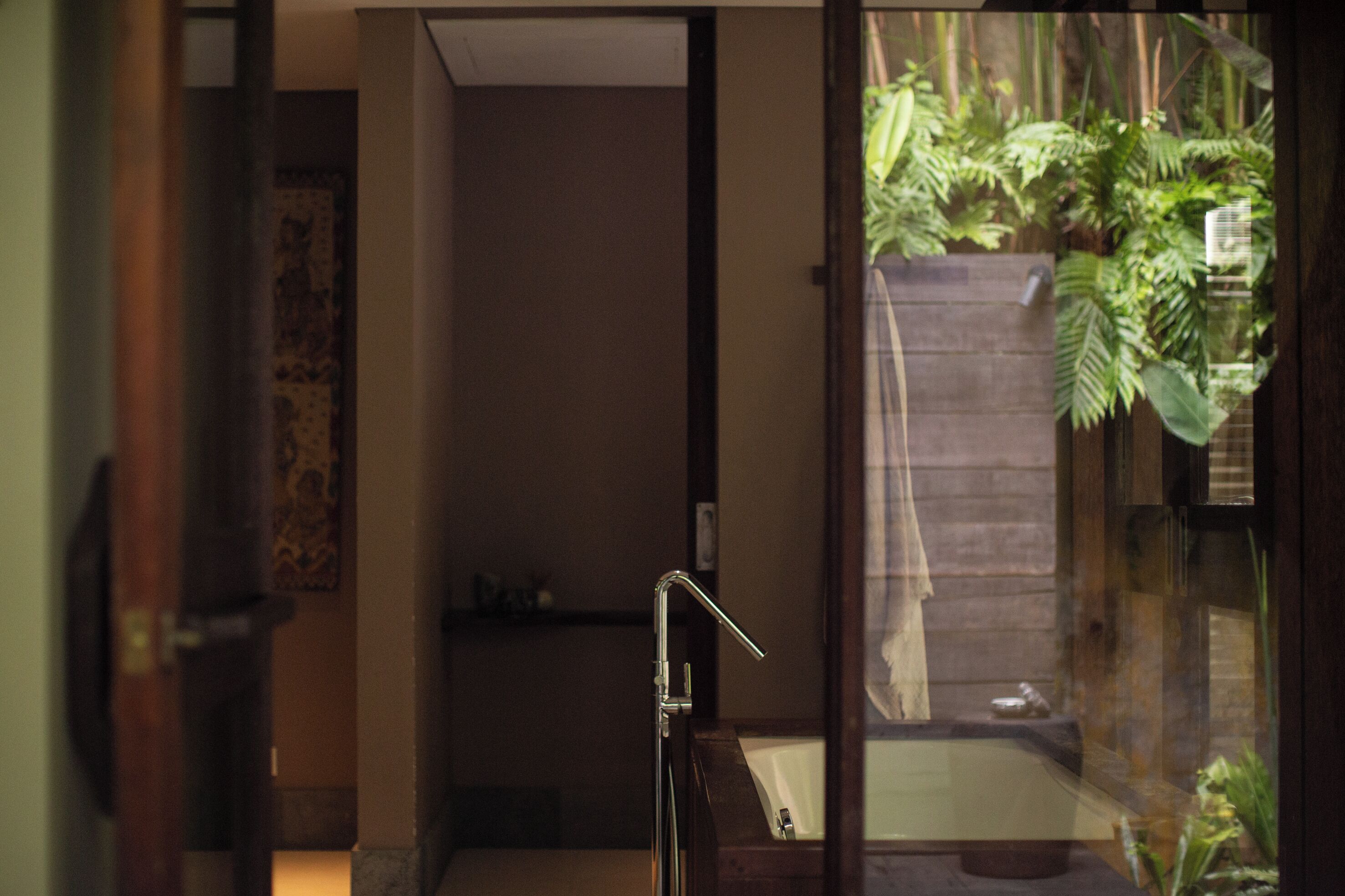 A bathroom with a bathtub, a shower, and a glass door leading to a garden.