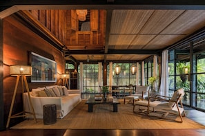 Un vaste espace de vie doté d’un haut plafond, de lambris en bois, d’une grande fenêtre et d’un mobilier confortable.