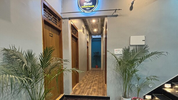 A hotel entrance with a modern design, featuring a patterned floor, potted plants, and a sign above the door. - Hotel Sangam Village (Karchana)