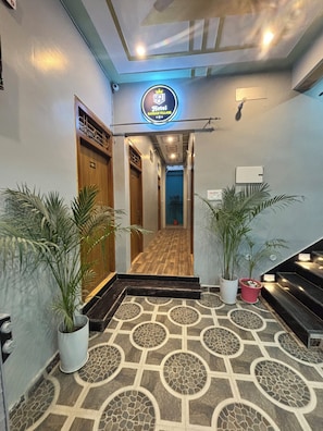 A hotel entrance with a modern design, featuring a patterned floor, potted plants, and a sign above the door. - Hotel Sangam Village (Karchana)