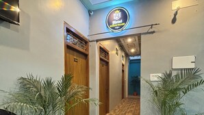 A hotel lobby with a patterned floor, wooden doors, and potted plants. - Hotel Sangam Village (Karchana)