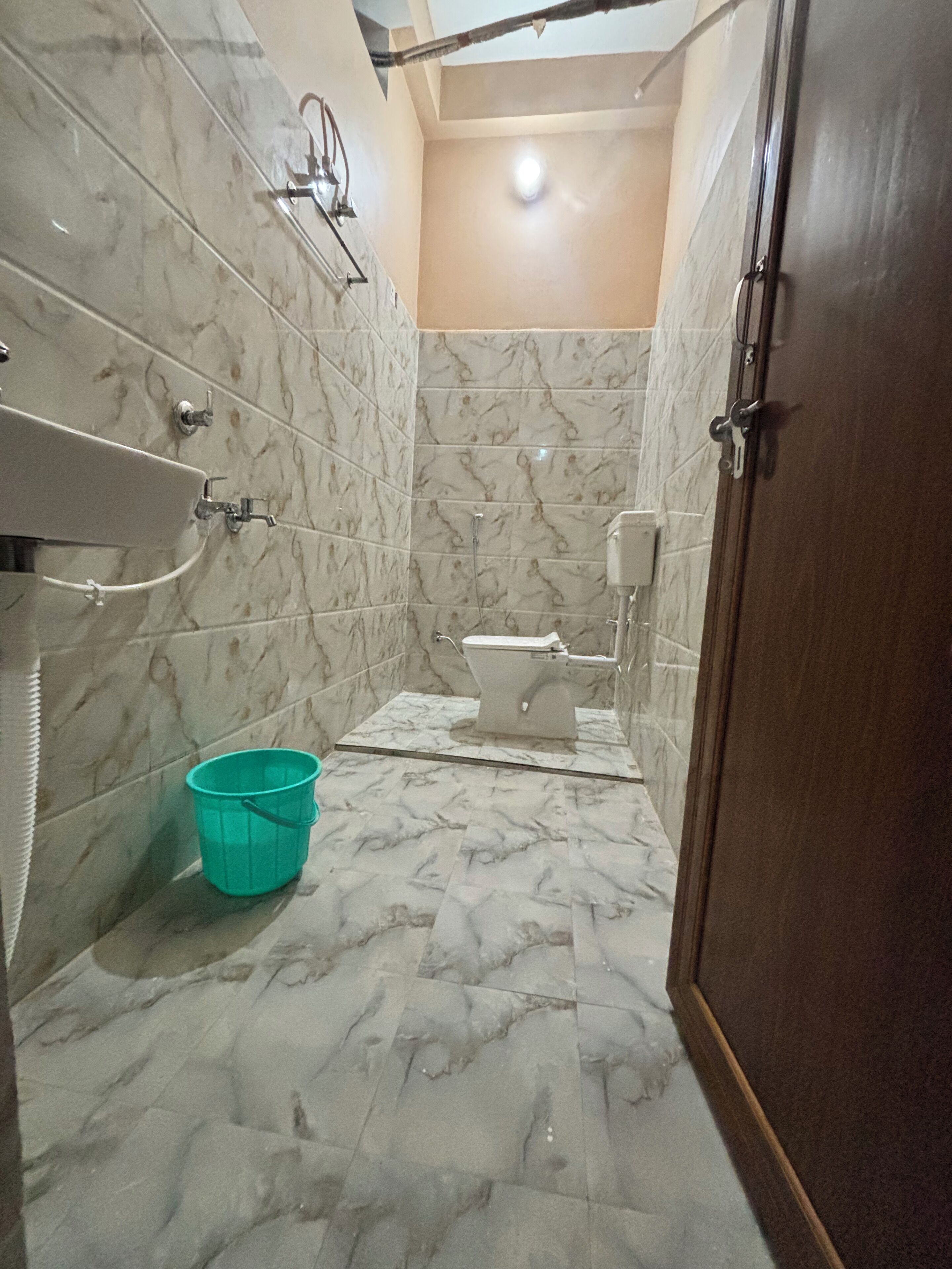 Une salle de bain avec des murs en marbre, des toilettes, un lavabo et une douche.