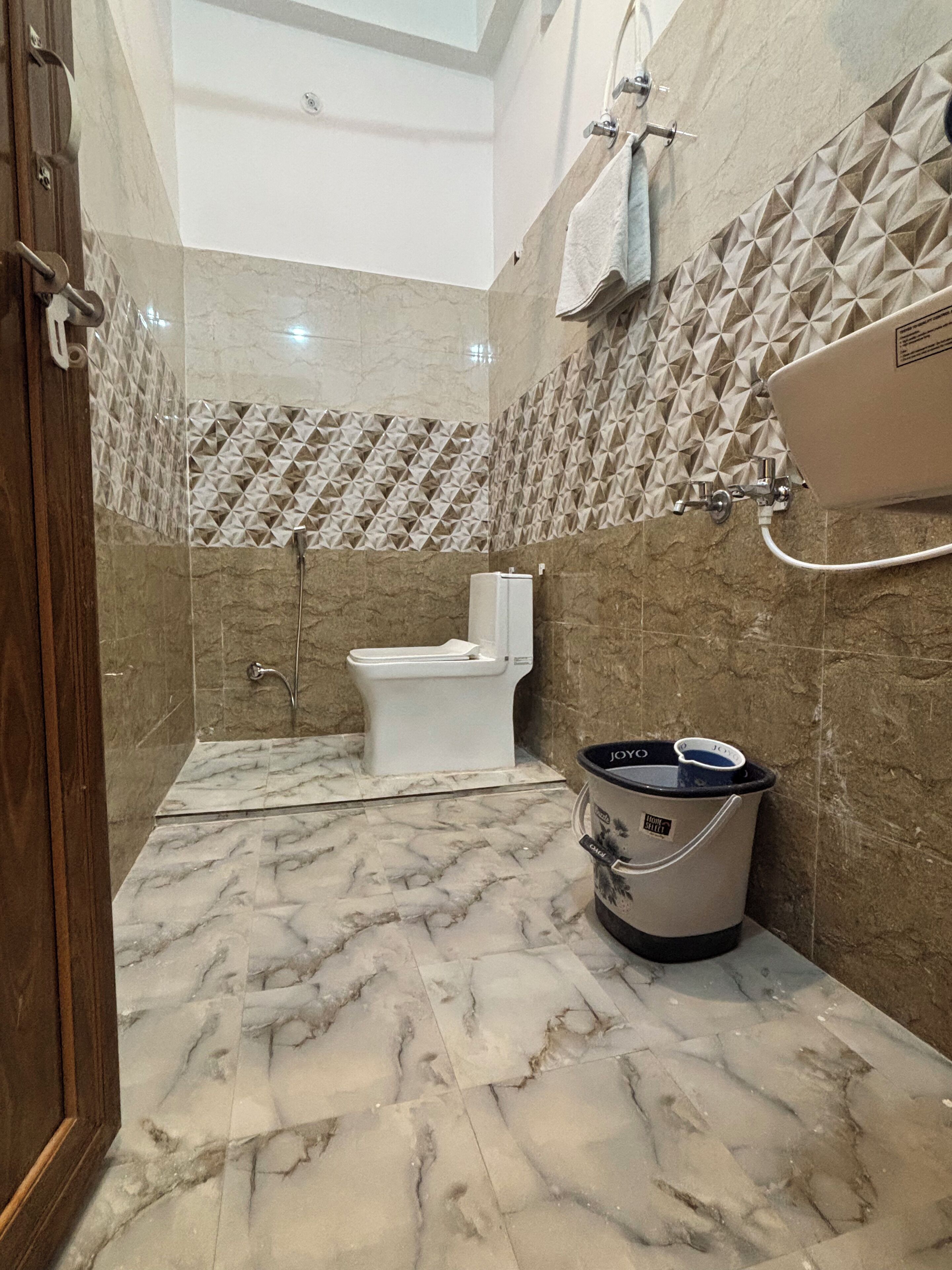 Ein Badezimmer mit Dusche, Toilette und einem Eimer.