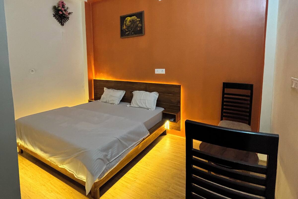Une chambre à coucher comprenant un lit, une chaise, un ventilateur de plafond et un tableau accroché au mur.