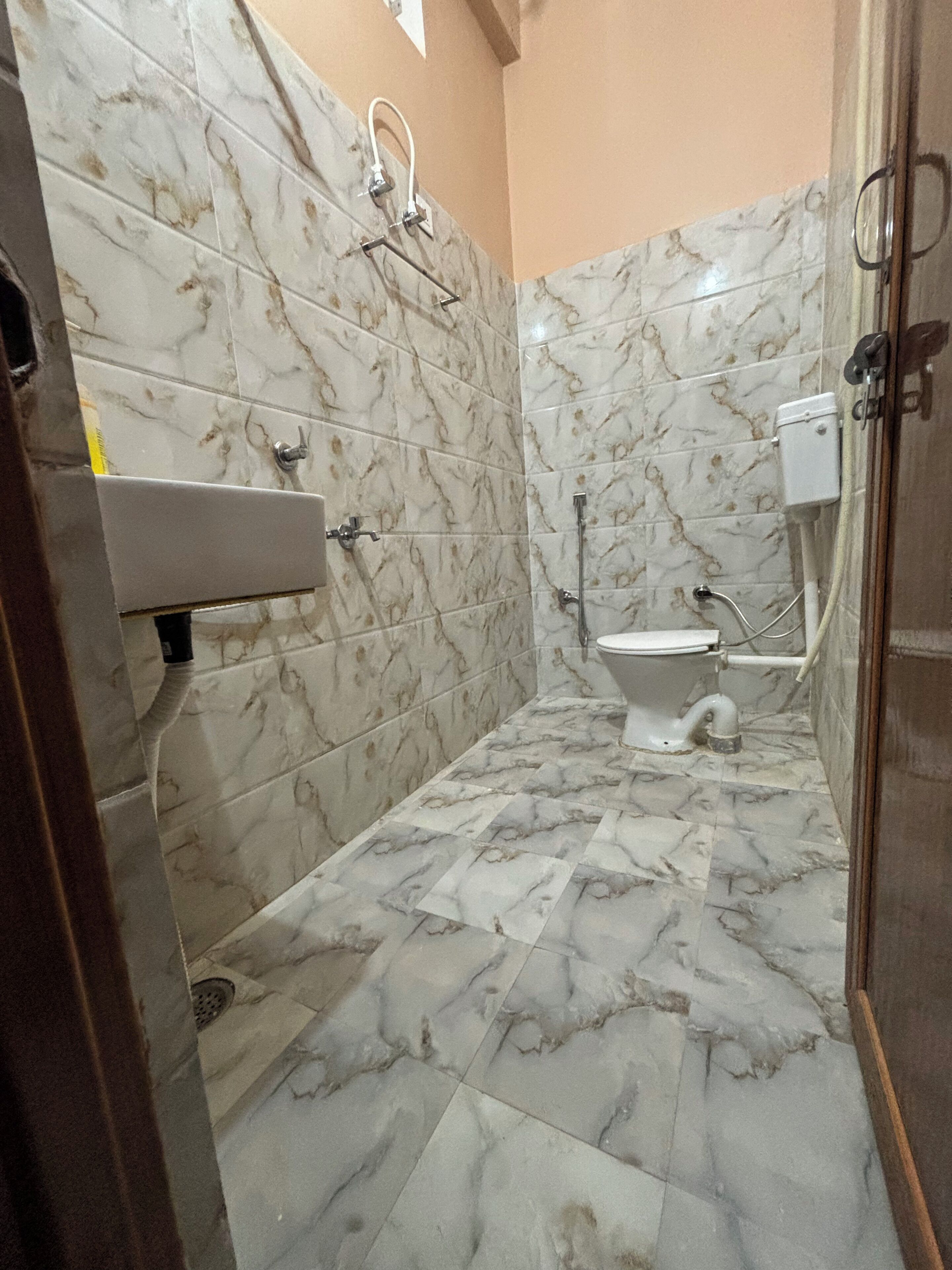 Ein Badezimmer mit Marmorfliesen, einer Toilette, einem Waschbecken und einer Dusche.
