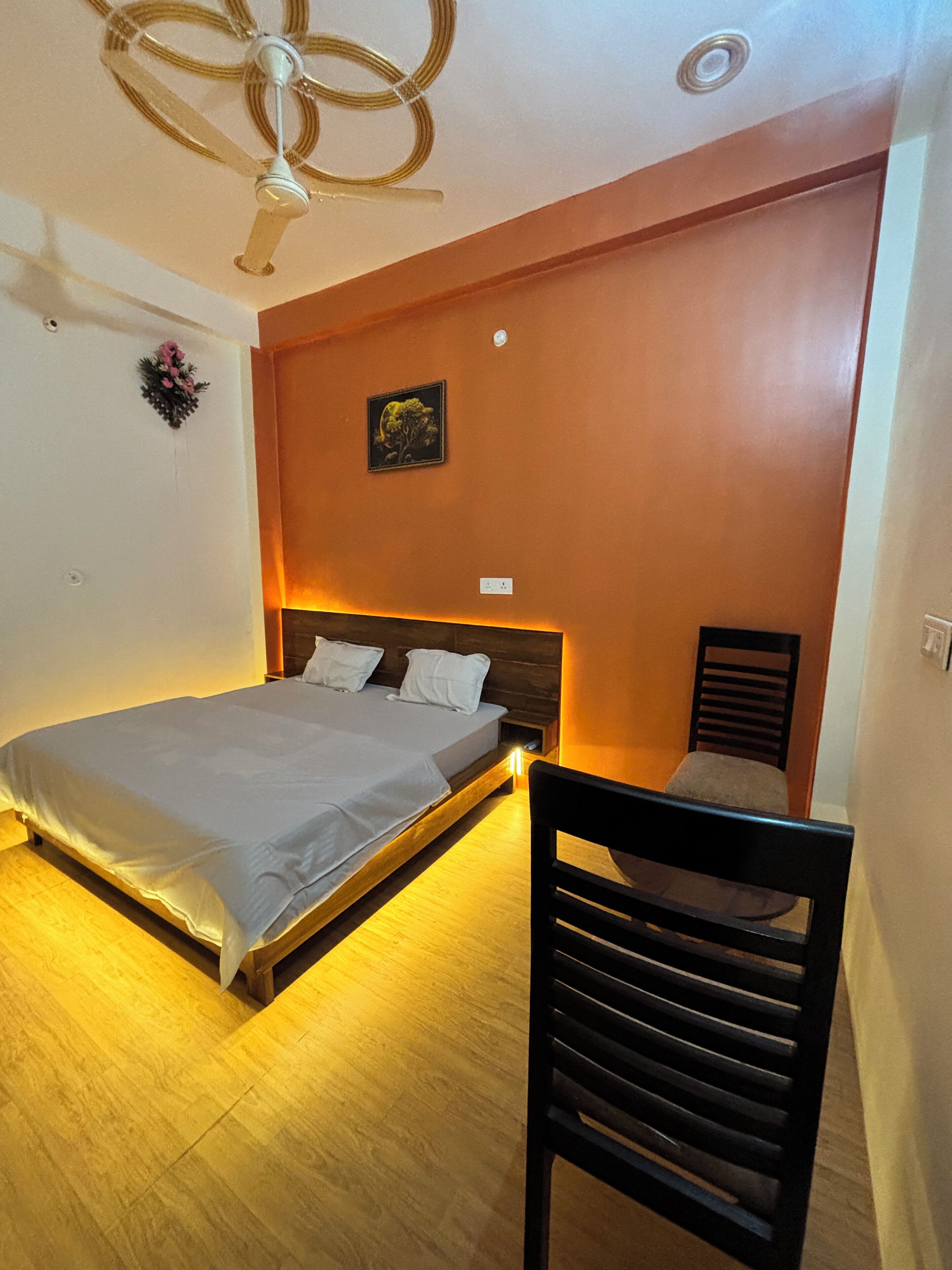 A bedroom with a bed, a chair, a ceiling fan, and a wall-mounted picture.