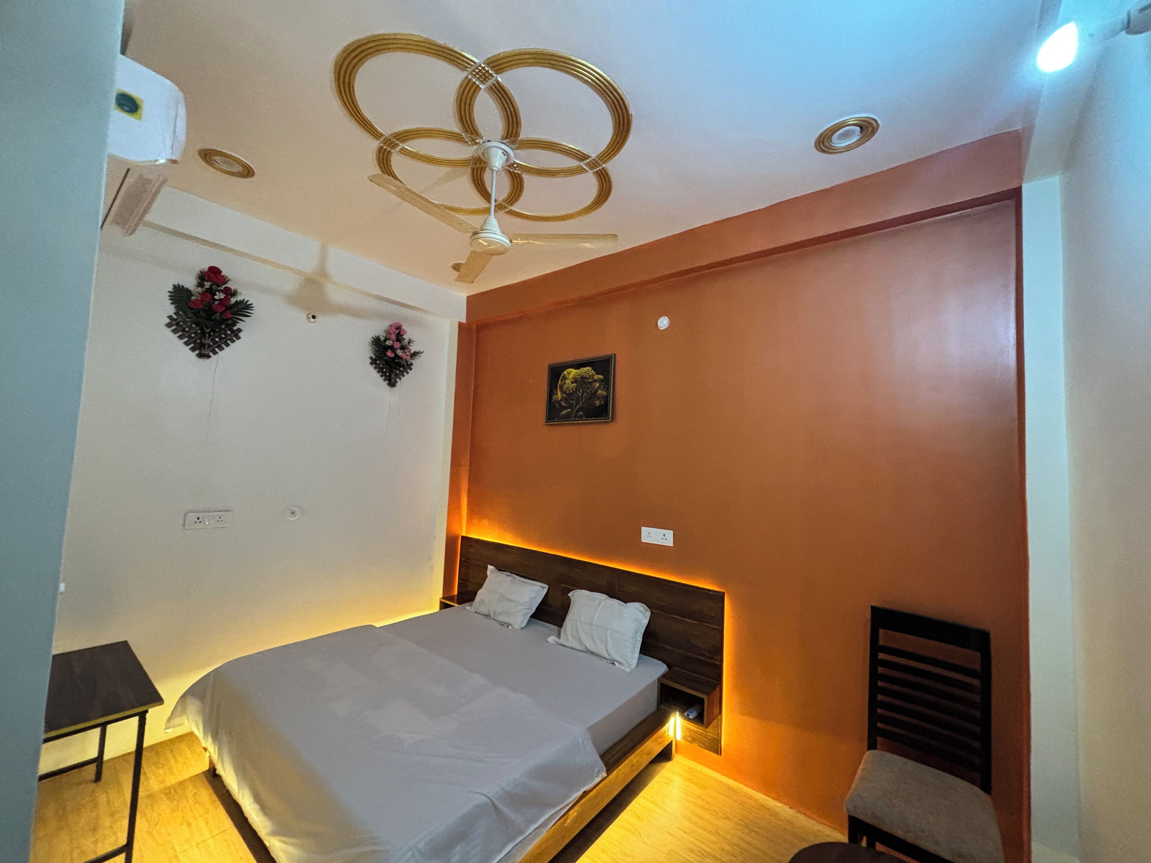 A bedroom with a bed, a nightstand, a wall-mounted air conditioner, and a ceiling fan.