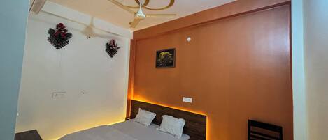 A bedroom with a bed, a nightstand, a wall-mounted air conditioner, and a ceiling fan.