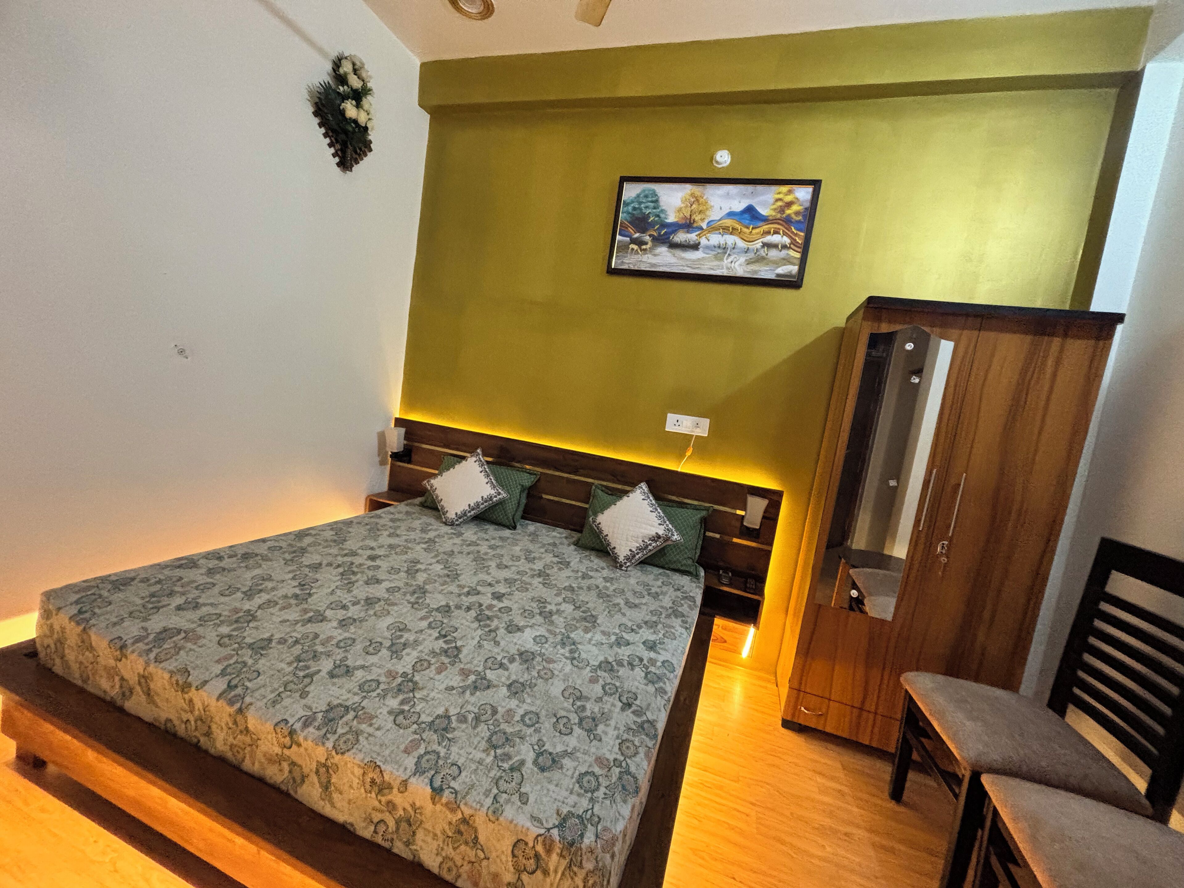 A bedroom with a bed, wooden headboard, green wall, and a painting.