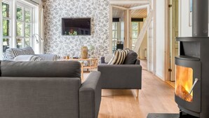 Ein gemütliches Wohnzimmer mit Kamin, einem an der Wand befestigten Fernseher und einer Treppe zu einer weiteren Ebene.