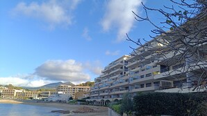Um hotel à beira-mar com várias varandas, uma praia arenosa e vista clara do mar.