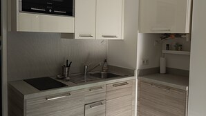 Uma cozinha moderna com micro-ondas embutido, pia de aço inoxidável e armários de madeira.