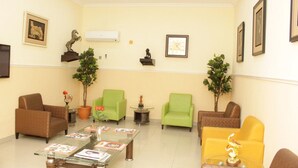 Una zona de recepción con una mesa de centro de vidrio, varias sillas y plantas decorativas.