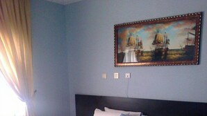 Una habitación de hotel con una cama grande, un cuadro en la pared y una alfombra estampada.