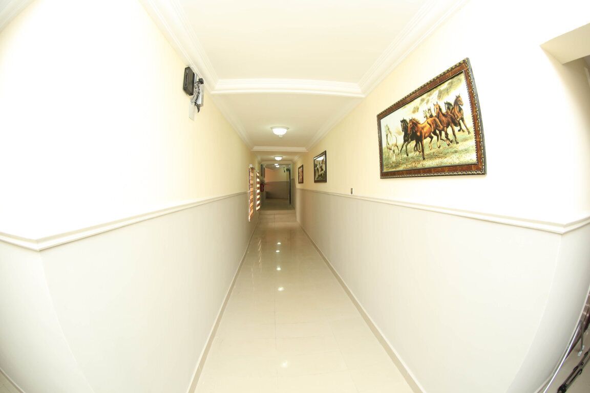 A hallway with white walls, a polished floor, and framed artwork on the walls.