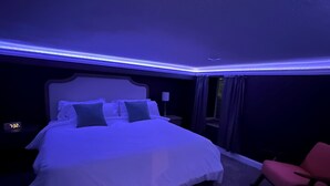 Une chambre à coucher avec un lit, une table de chevet, une chaise rouge et une horloge.