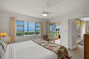 Une chambre d’hôtel avec un lit, une chaise, un ventilateur de plafond et une vue sur l’océan.