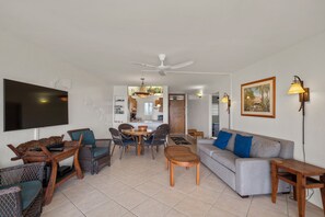 Un salon comprenant un canapé, des fauteuils, une table basse, un téléviseur et un ventilateur de plafond.