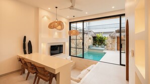 A modern kitchen with a dining area, large windows, and a view of an outdoor pool. - Villa Kaia by Alfred in Bali (Canggu)