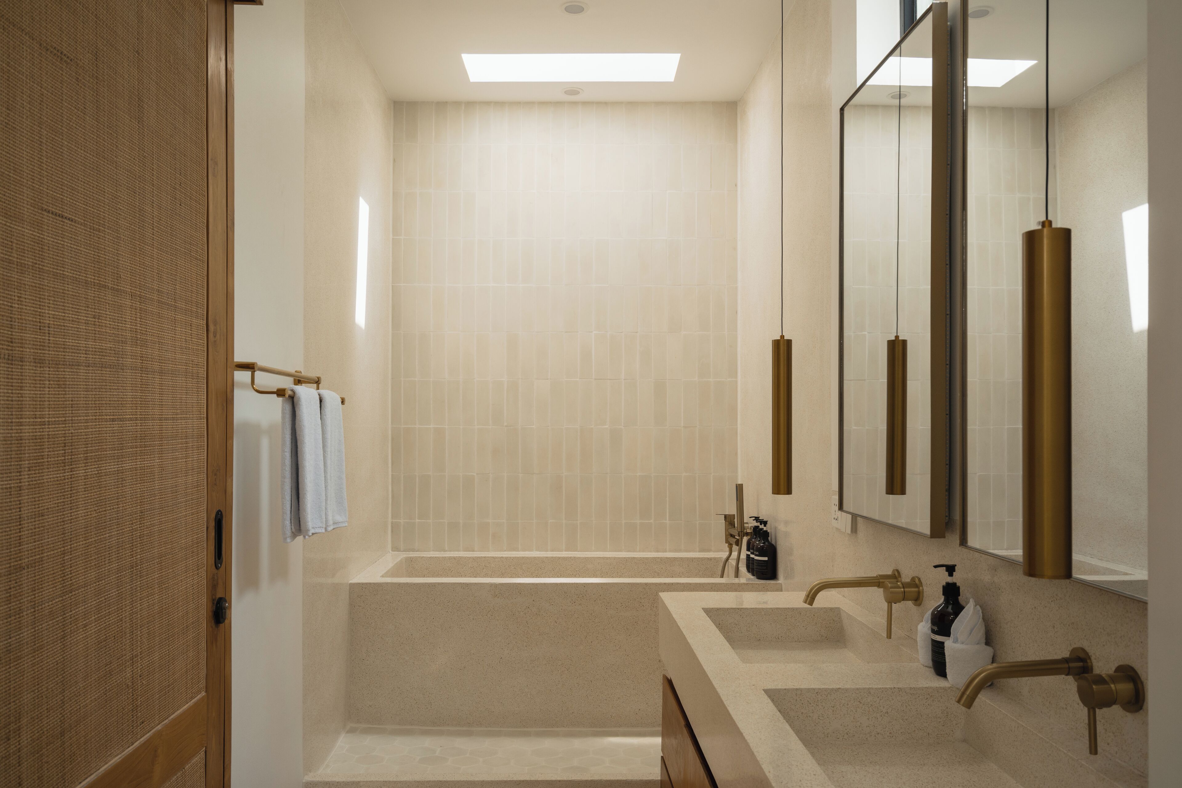 Ein modernes Badezimmer mit einer großen Badewanne, zwei Waschbecken und einem Spiegel.
